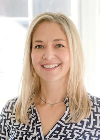 A woman with blonde hair and wearing a black and white shirt.